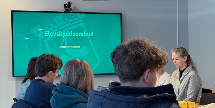 En grupp ungdomar sitter i ett klassrum och tittar på en presentation om elevskyddsombud.