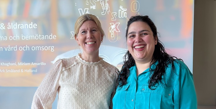 Två personer står framför en presentation med text och symboler projicerade på väggen bakom dem.