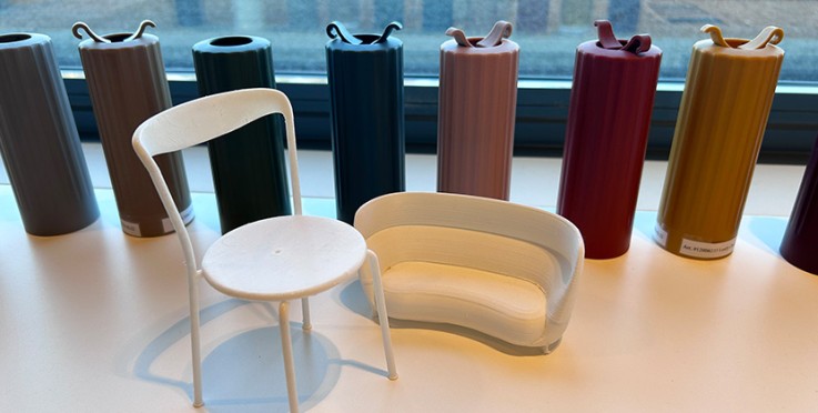 Små modeller av en stol och soffa står på ett bord framför färgprover i olika nyanser.