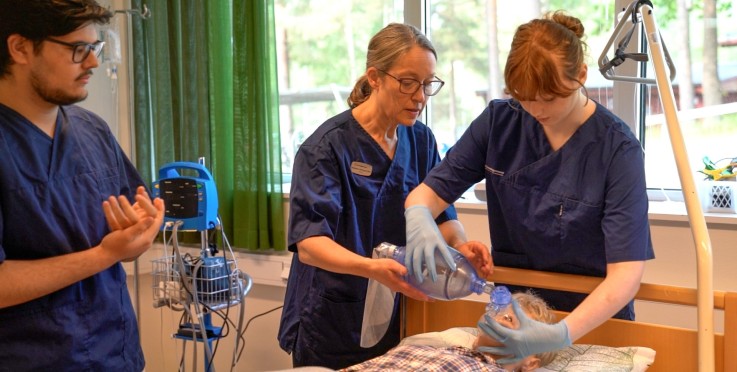 Tre vårdpersonal ger akut andningshjälp till en patient i en sjukhussäng.