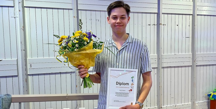 En person som fått stipendie. Han håller i diplom och blommor.