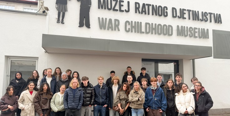 En grupp människor står framför War Childhood Museum i Sarajevo, utanför byggnadens entré.