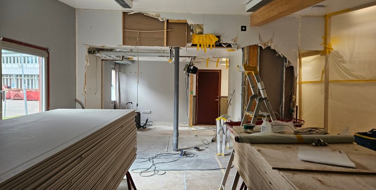 Ett rum under renovering med rivna väggar, byggmaterial, stege och verktyg.