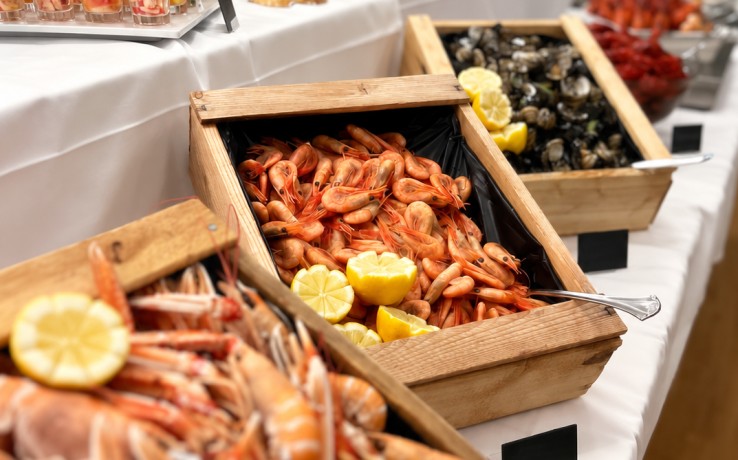 Buffébord med skaldjur som räkor, kräftor och musslor i trälådor, dekorerat med citroner.